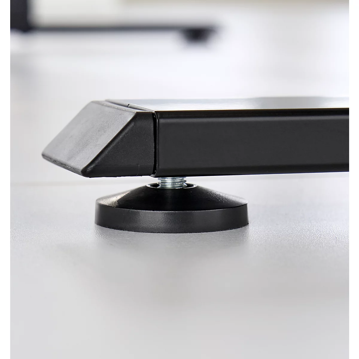 Close-up van een zwart tafelbeen met verstelbare voet. Op een licht oppervlak, gedetailleerde opname.