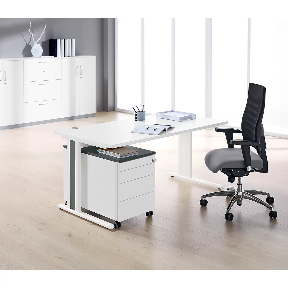 Un bureau lumineux avec une chaise de bureau. Des papiers et des stylos sont posés sur la table, une armoire de classement en arrière-plan.