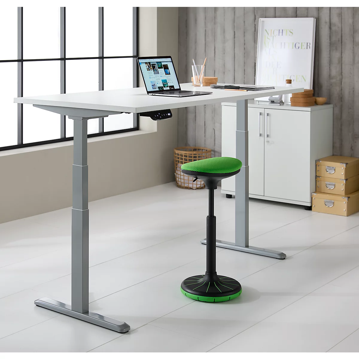 Statafel met laptop, stoel, mand, kast en wanddecoratie.