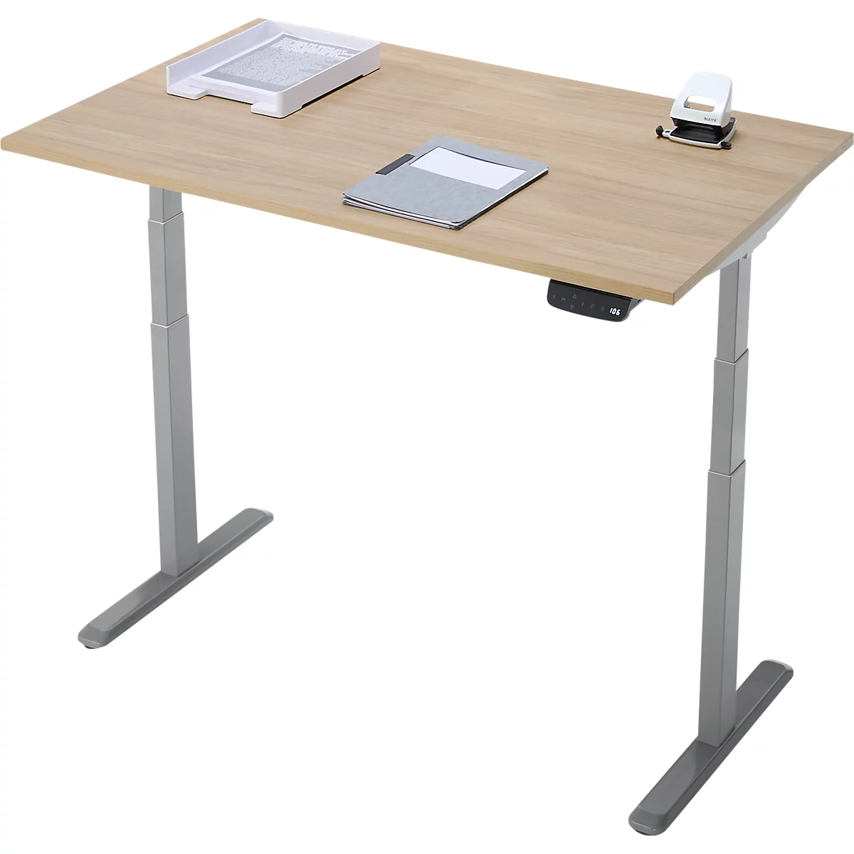 Un bureau à hauteur réglable avec plateau en bois et pieds gris. Un bac à papier, un bloc-notes et une perforatrice sont posés sur le dessus.