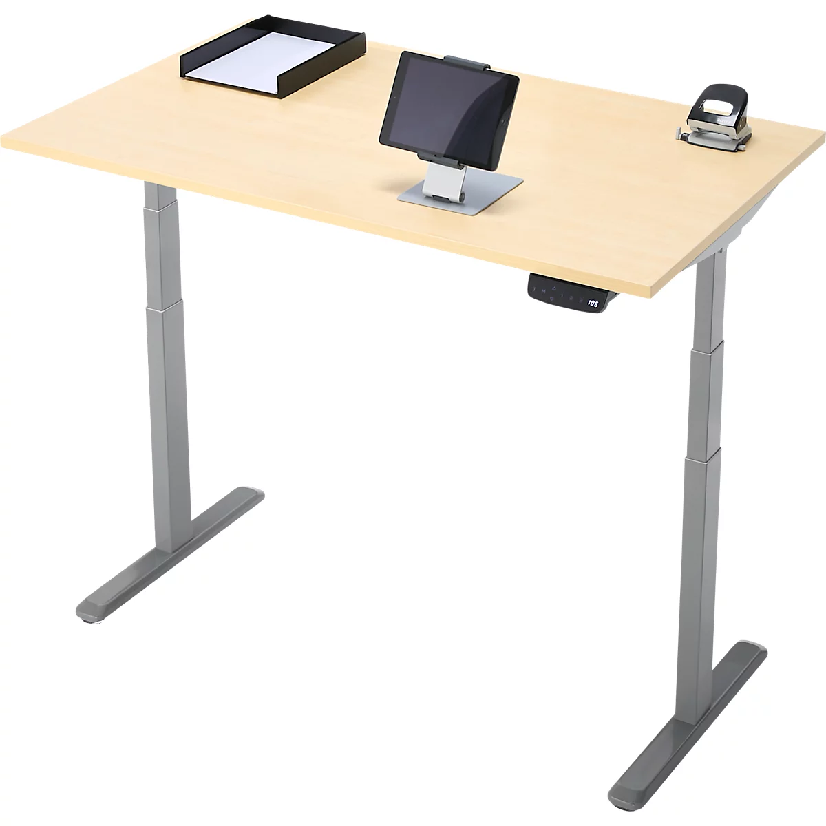 Un bureau réglable en hauteur en bois clair. Sur le plateau se trouvent une tablette, un porte-papier et une perforatrice.