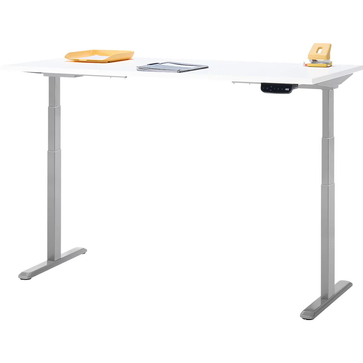 Un bureau réglable en hauteur avec un plateau blanc et des pieds gris, sur lequel sont placés un plateau et une perforatrice.