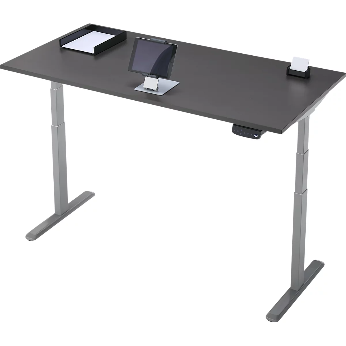 Bureau réglable en hauteur, gris foncé, avec tablette, porte-papier et bloc-notes. Le bureau repose sur deux pieds gris.