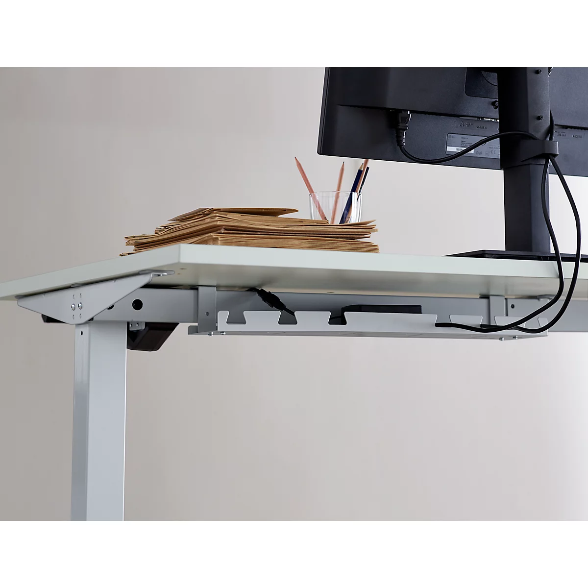 Bureau avec gestion des câbles, moniteur, stylos et paperasse. Détails de la construction du bureau.