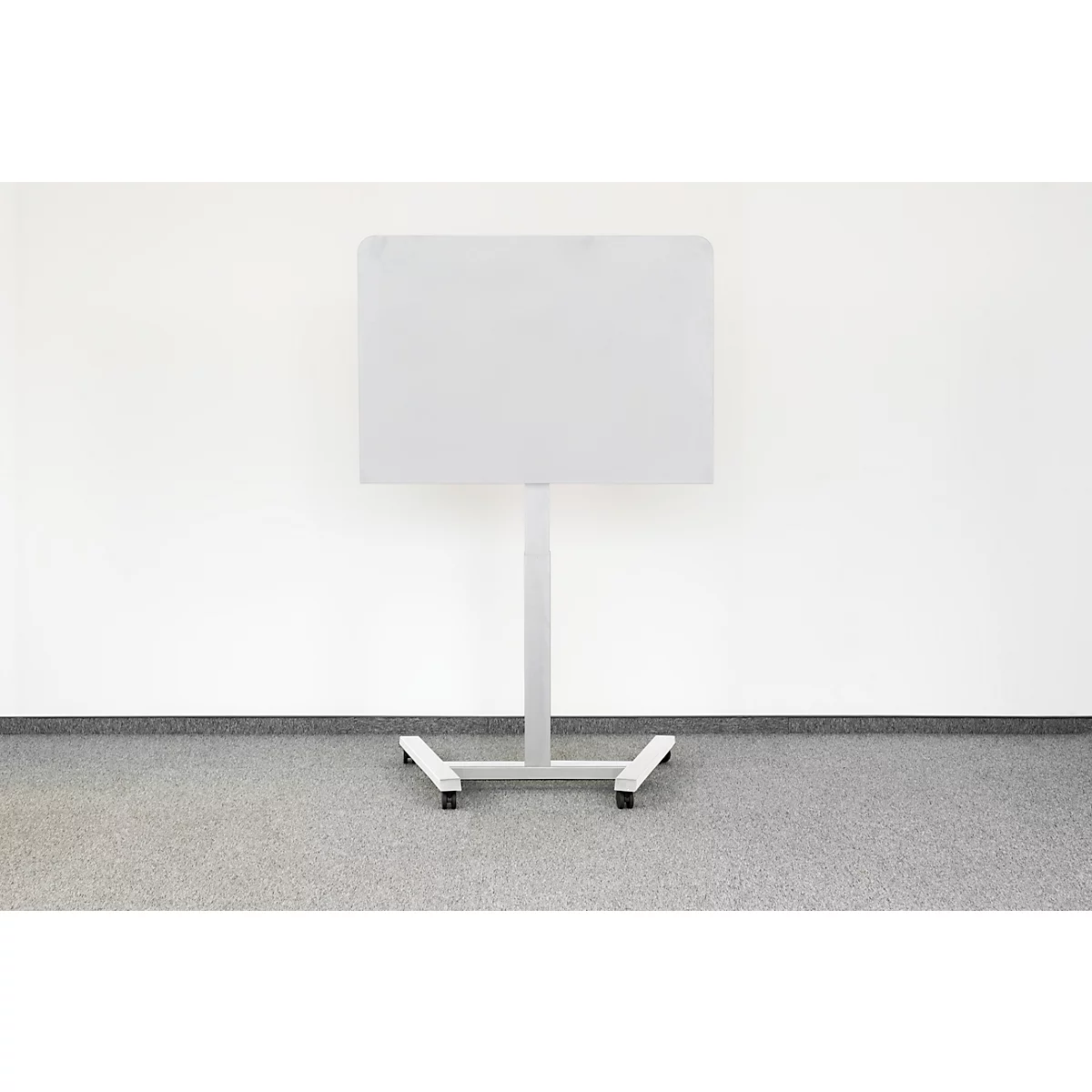 Tableau blanc sur un support métallique devant un mur blanc. Sol gris.