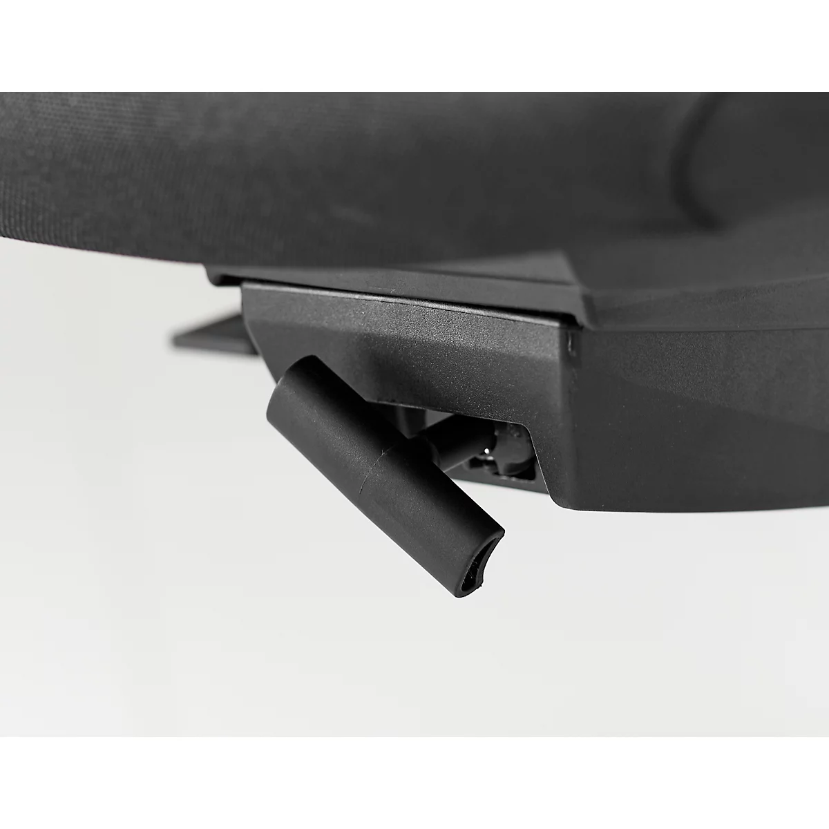 Close-up van een zwarte plastic handgreep bevestigd aan een zwart, hoekig onderdeel. Op de achtergrond een donkere stof.