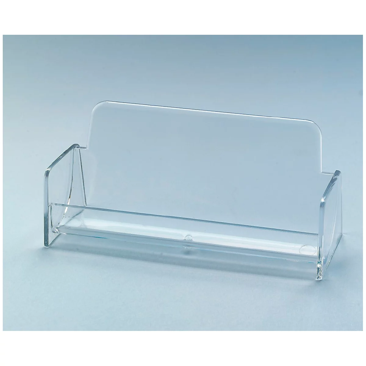 Transparent business card holder made of acrylic glass, with back and side parts. The holder stands on a light blue surface.