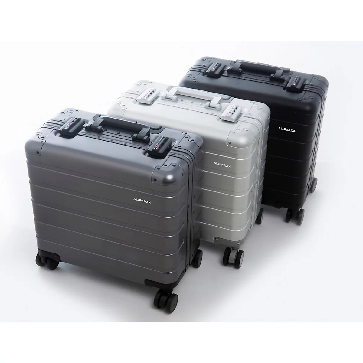 Drie aluminium koffers in grijstinten, zilver en zwart. Voorzien van wielen en handvatten, staan ze naast elkaar op een witte achtergrond.