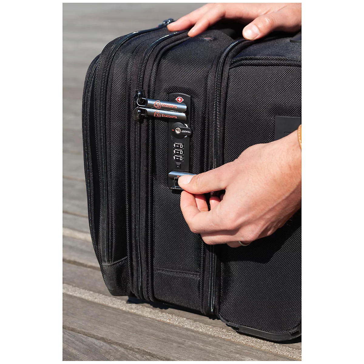 Close-up of a man opening a black luggage with a combination lock.