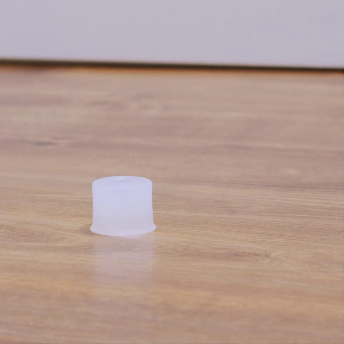 Un objet blanc de forme cylindrique est posé sur une surface en bois. L'arrière-plan est flou.