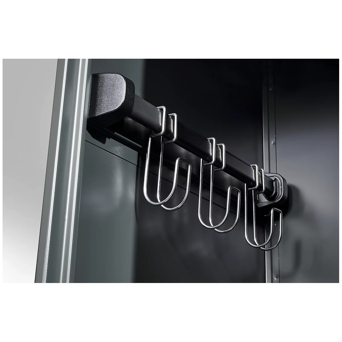 Black hook strip with metal hooks on wall.