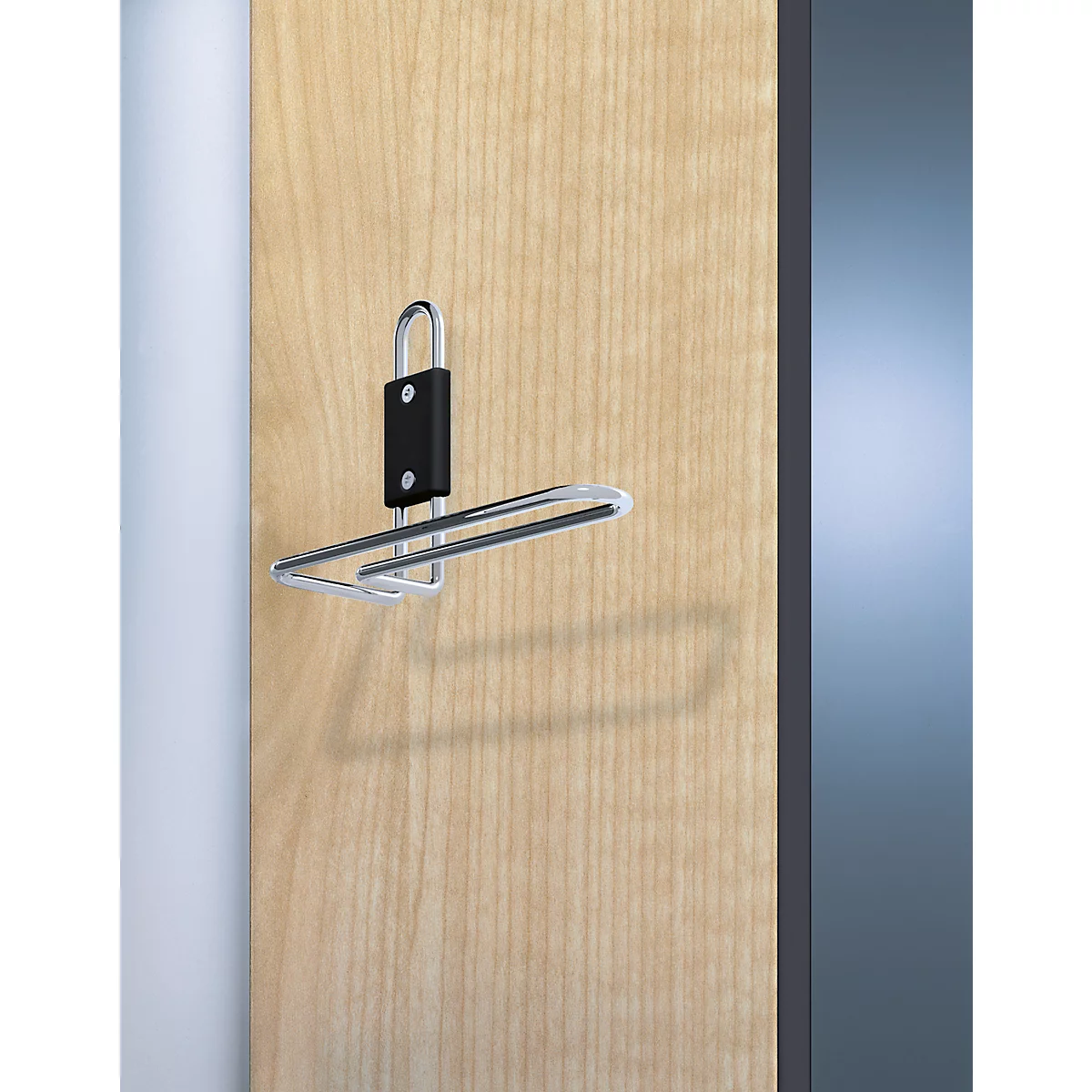 Metallhaken mit schwarzem Halter an Holzoberfläche. Der Haken wirft einen Schatten. Rechts ein graublauer Bereich.