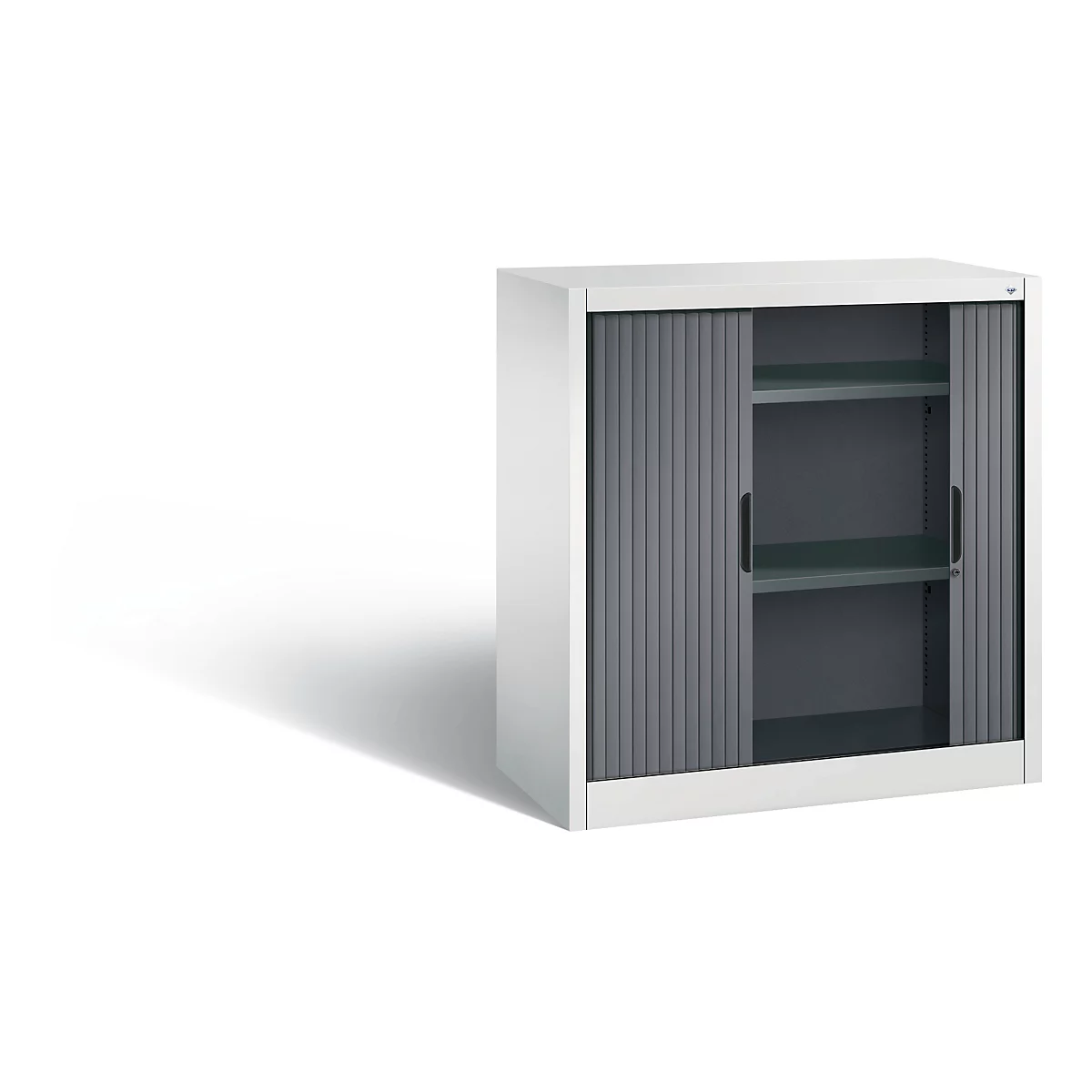 White filing cabinet with gray roller shutters, two interior shelves and black handles. Shadow on the left.