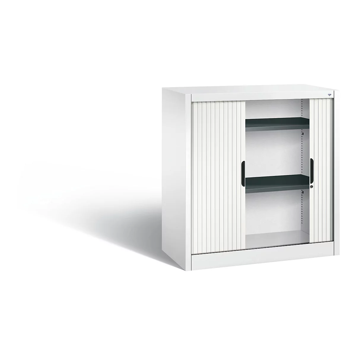 White cabinet with roller shutters. Black handles and two shelves. Shadow on the left.