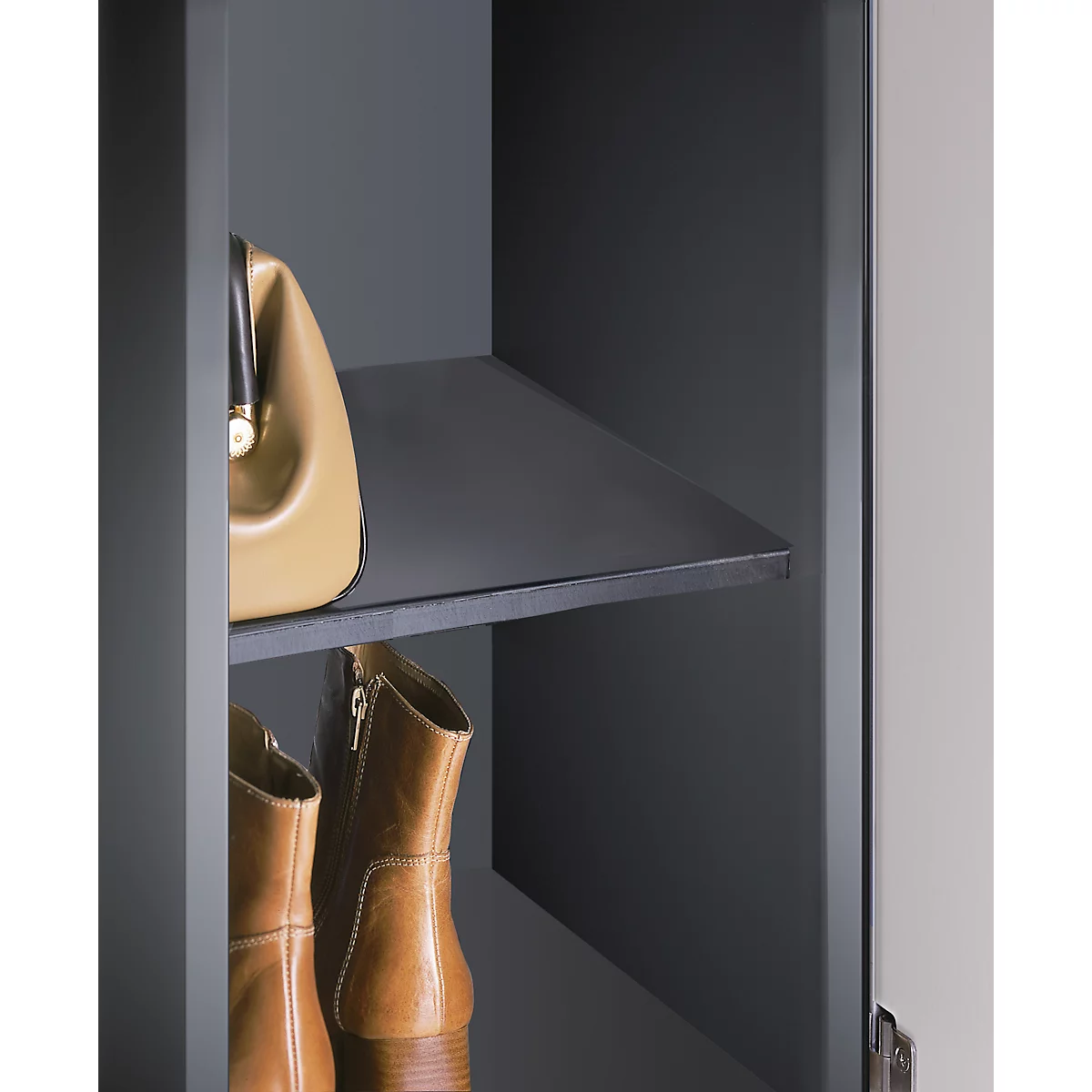 Beige Handtasche und braune Stiefel in einem grauen Schrank.