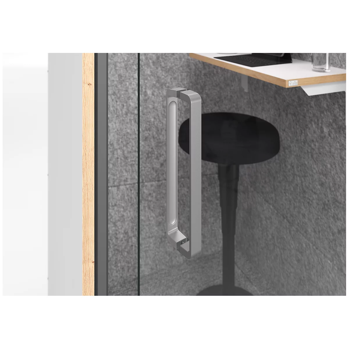 Gros plan : poignée de porte argentée sur la porte vitrée d'une cabine téléphonique de bureau. A côté, un tabouret noir et une table blanche.