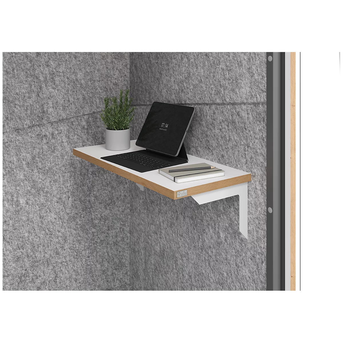 Dans un coin gris, une étagère blanche avec un ordinateur portable, une plante et des notes.