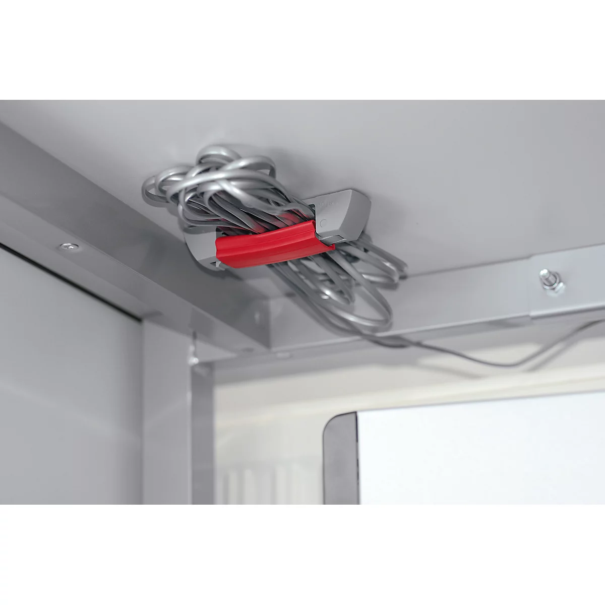 Silver cables held by a red band, attached to the ceiling. Bright environment.