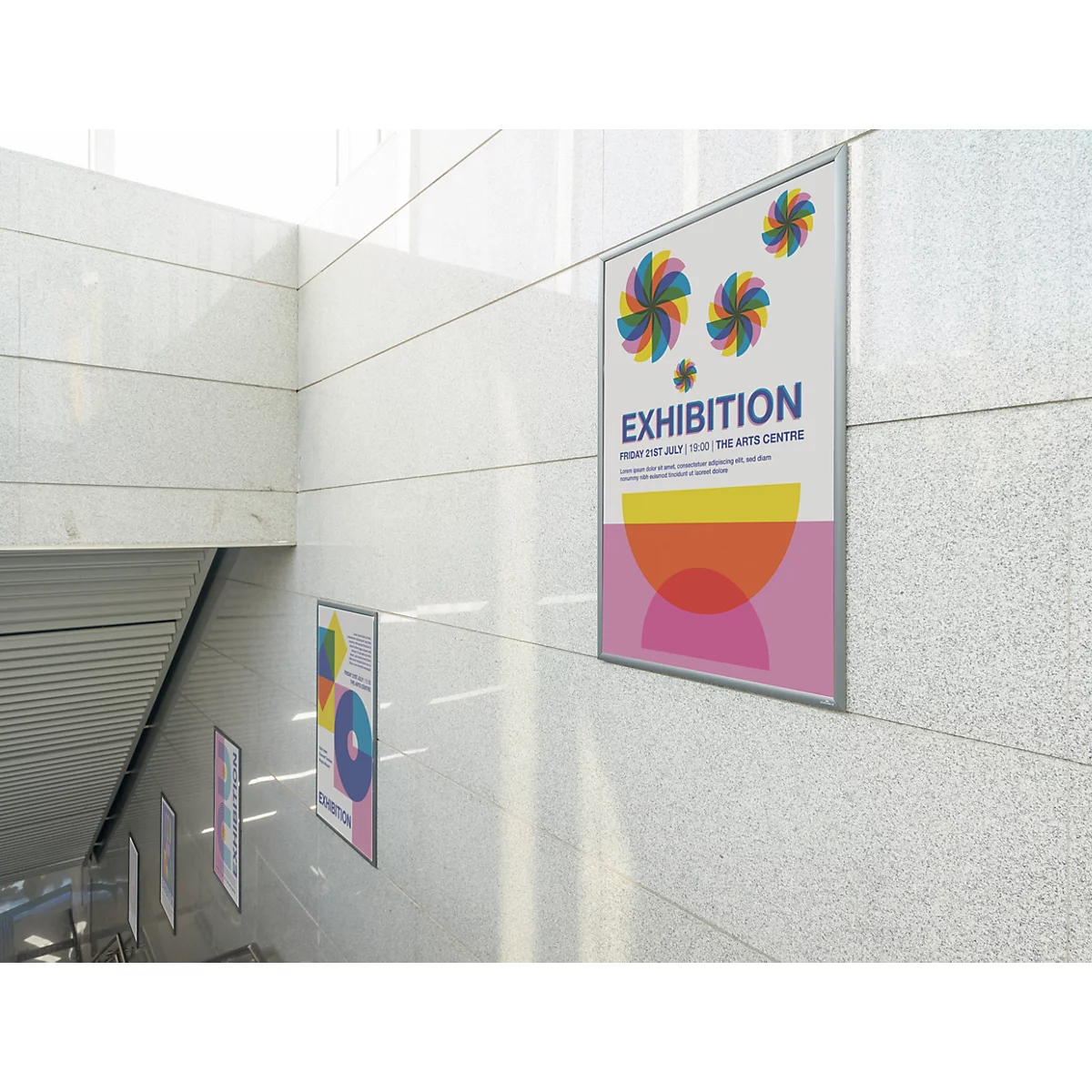 Plusieurs affiches d'exposition sont accrochées sur un mur clair carrelé le long d'un escalier.