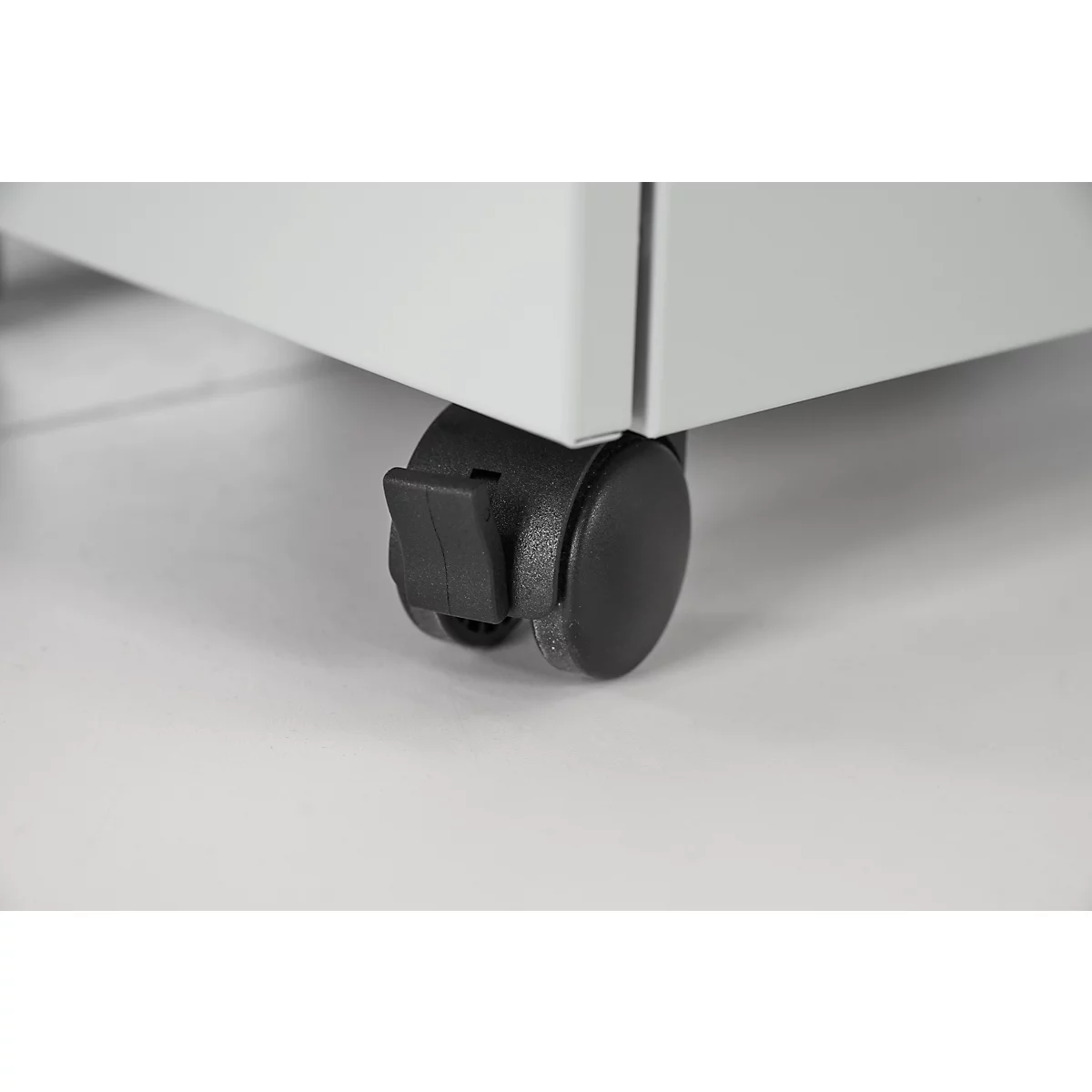 Gros plan d'une roulette noire sous un meuble blanc, détails.