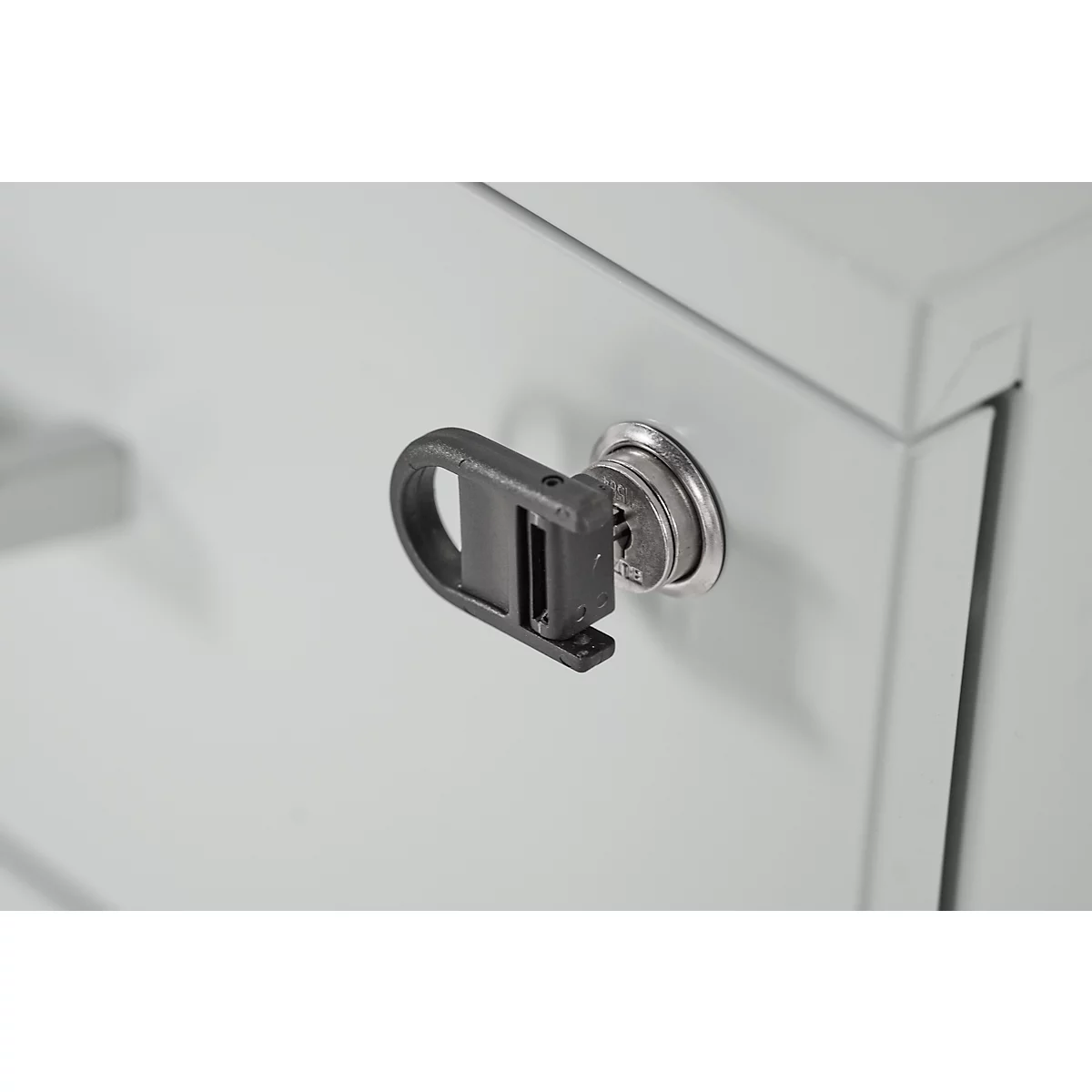 Gros plan d'une clé dans une serrure d'armoire. La clé est insérée dans la serrure argentée, avec une poignée noire.