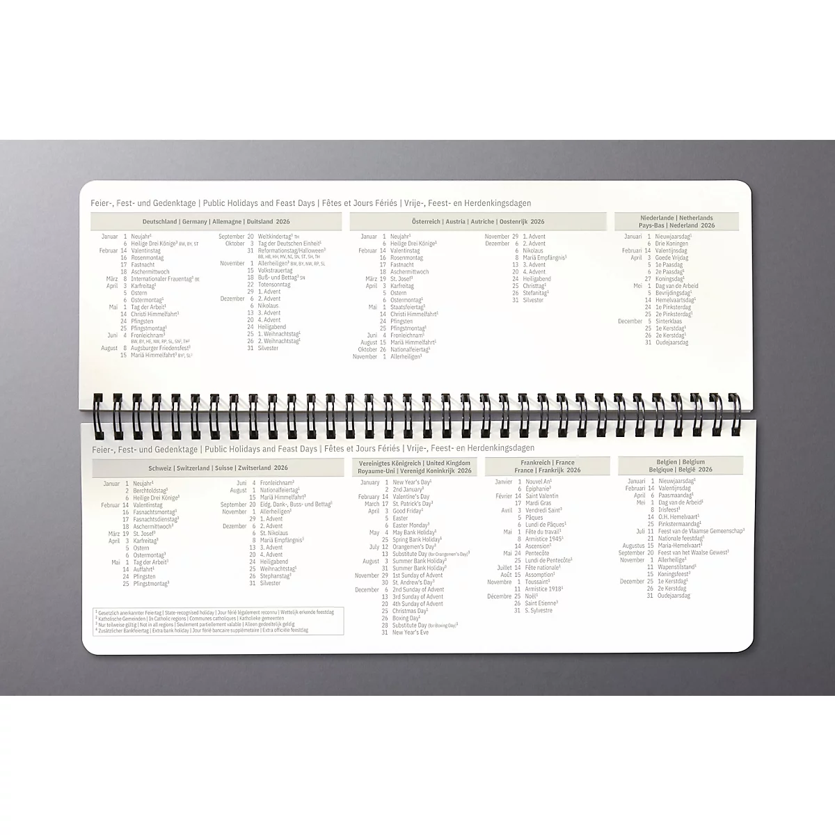 Carnet ouvert avec des tableaux. Les pages sont imprimées avec du texte gris, comprenant des jours fériés et des fêtes.
