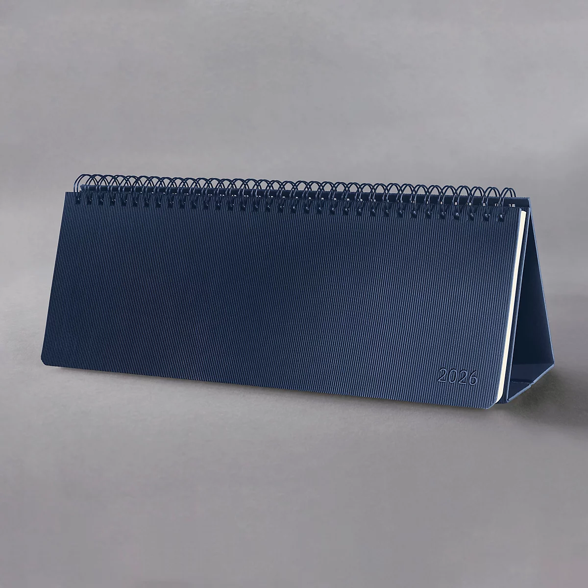 Calendrier de bureau bleu 2026 avec reliure à spirales, sur fond gris.