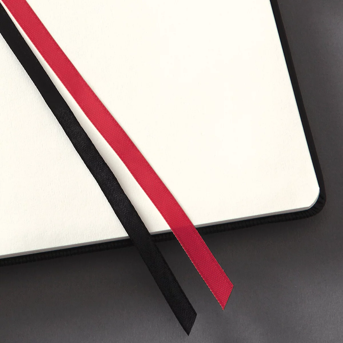 Gros plan d'un carnet avec des signets en ruban rouge et noir dépassant du coin.