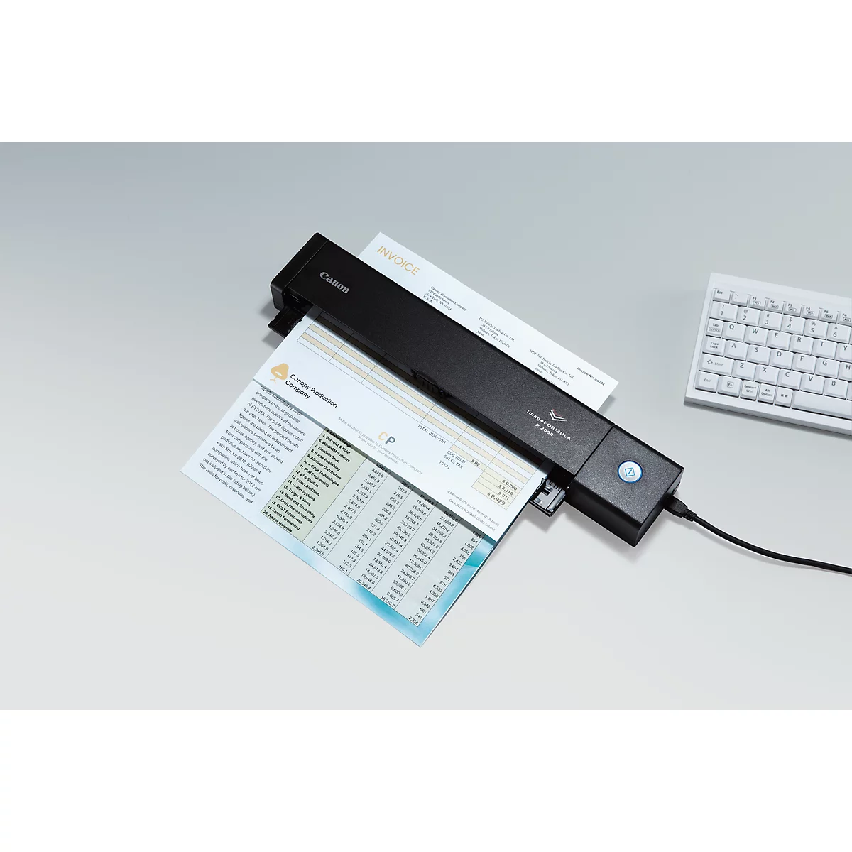 A black Canon scanner scanning documents. Part of the keyboard is visible in the background.