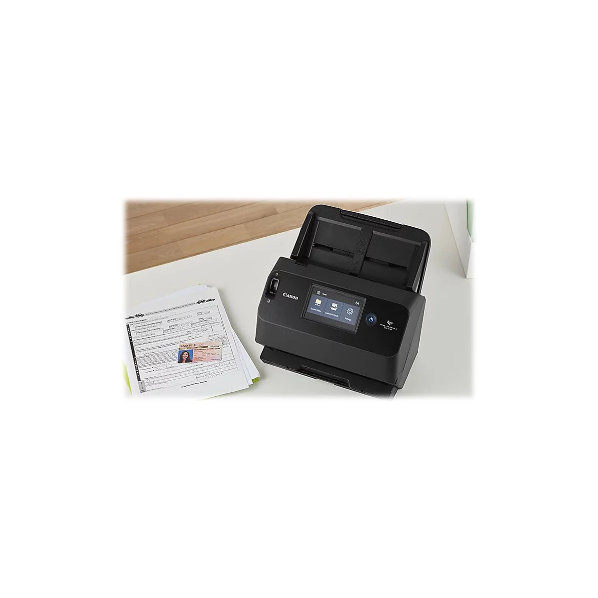 Ein schwarzer Canon-Scanner mit geöffnetem Deckel steht auf einem Schreibtisch. Daneben liegen Papiere und ein Personalausweis.
