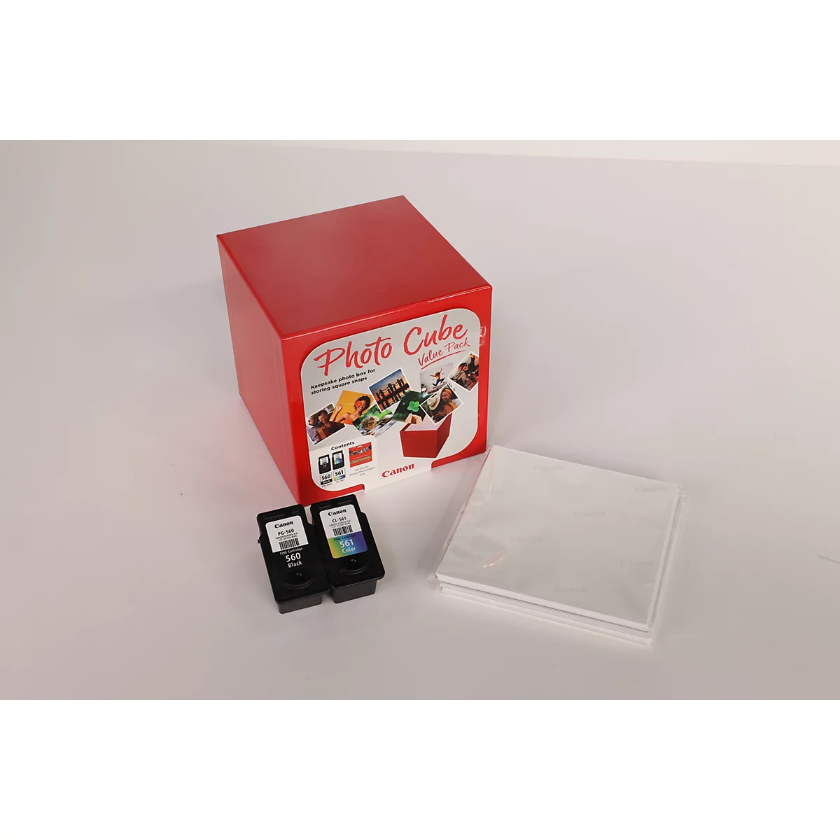 Roter Photo Cube-Kasten mit Aufdruck, Tintenpatronen und Fotopapier auf weißem Untergrund.