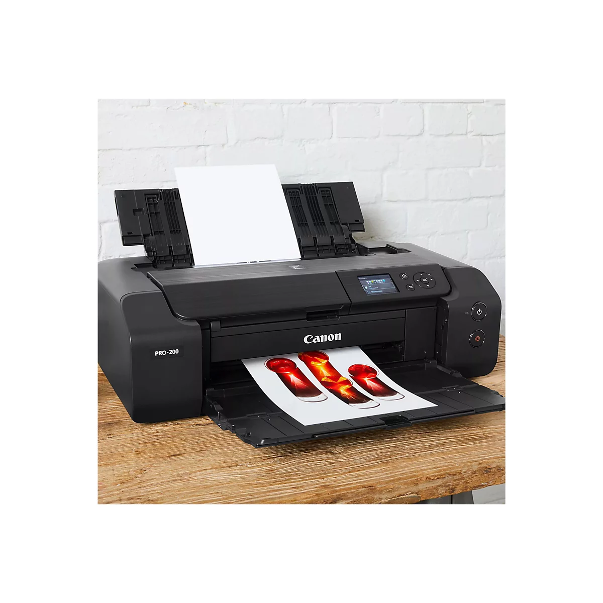 Schwarzer Canon PRO-200 Drucker, der ein farbiges Foto druckt. Papierausgabe offen. Auf einem Holztisch vor einer weißen Ziegelwand.