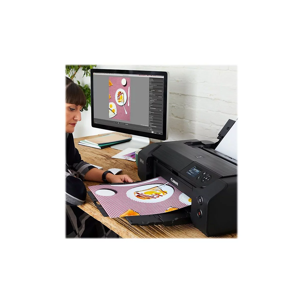 Eine Frau druckt ein Bild mit Essen auf einem Canon-Drucker, das auf einem Monitor entworfen wurde.