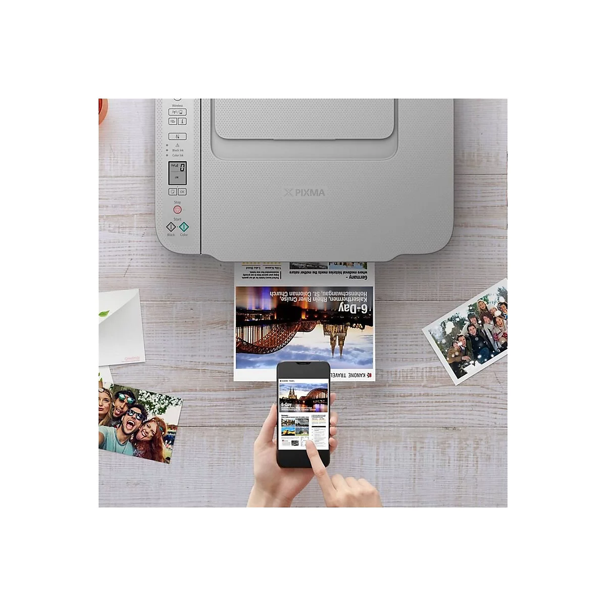 Drucker druckt Foto, daneben Handy mit App, Fotos liegen auf Holzuntergrund.