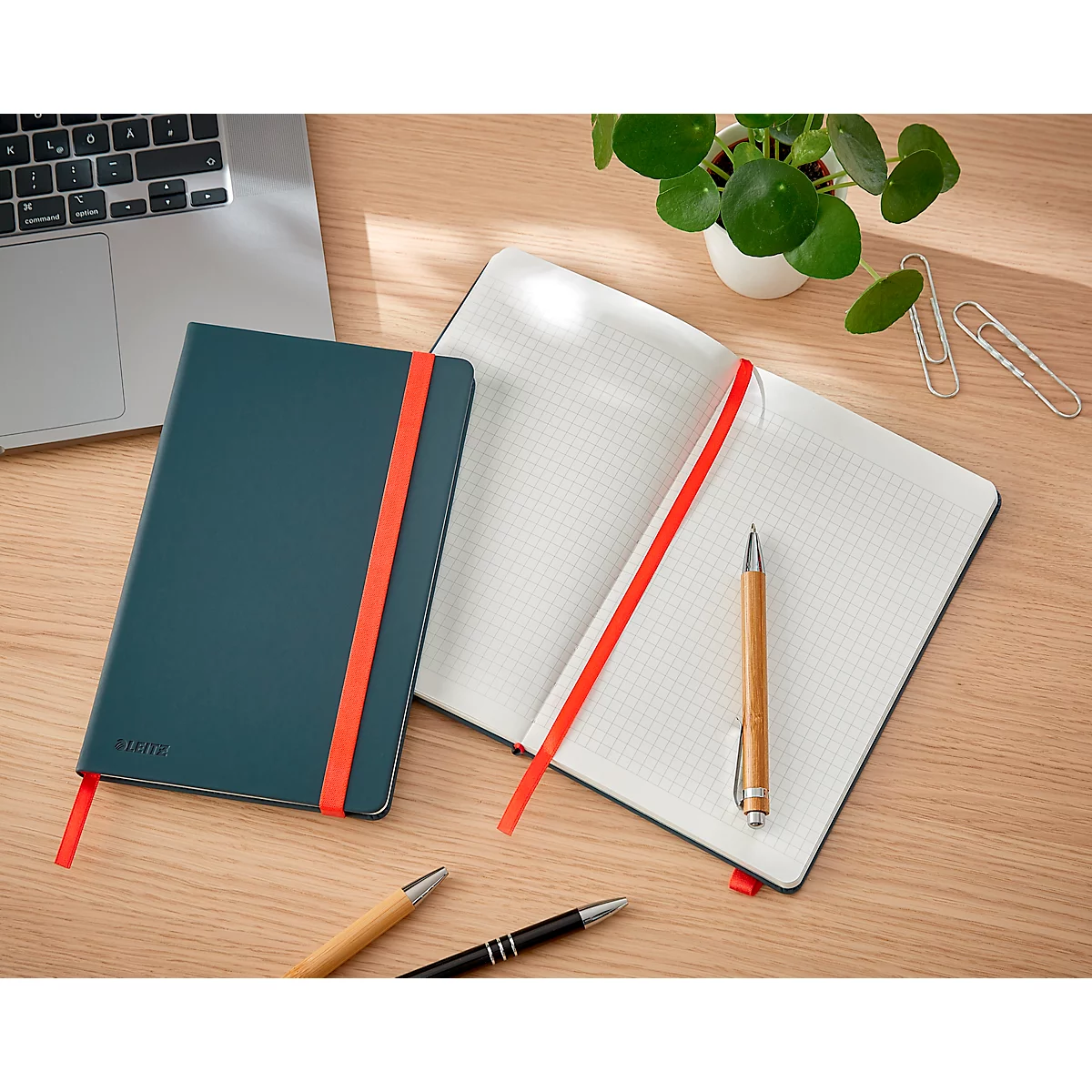 Carnet vert avec marque-page rouge. Carnet ouvert avec pages quadrillées et stylo. Sur surface en bois.