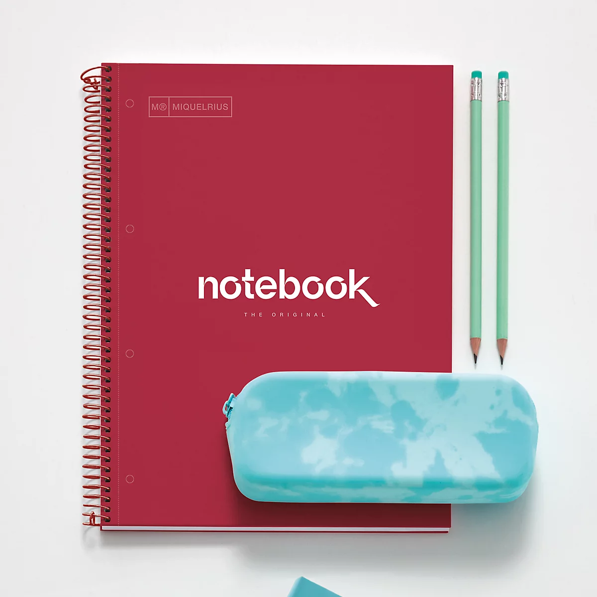 Cahier rouge, crayons et trousse bleu clair sur fond blanc.