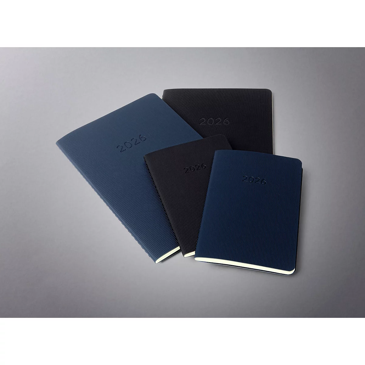 Vue de dessus de carnets de différentes tailles et couleurs, tous avec l'année 2026 en relief.