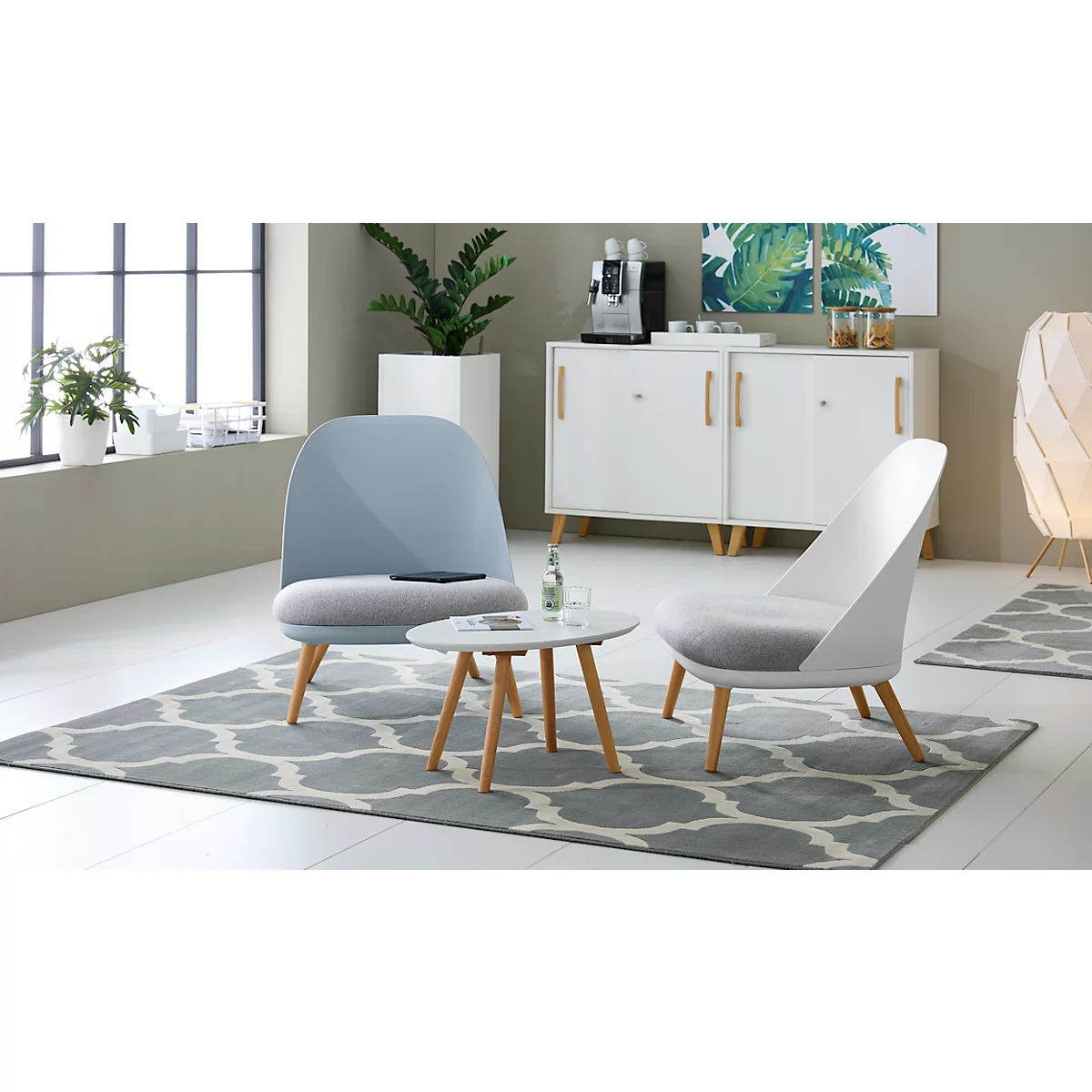 Two armchairs and a table in a living room. Blue and white furniture with wooden accents, on a grey carpet.