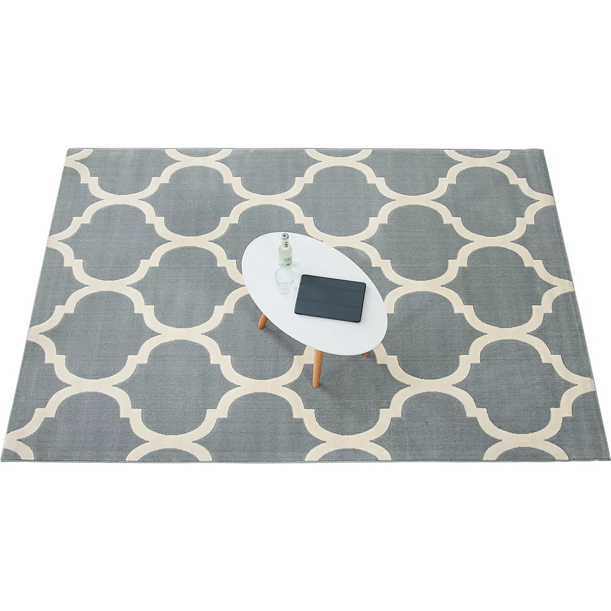 Gray rug with cream pattern, oval table with tablet and bottle.