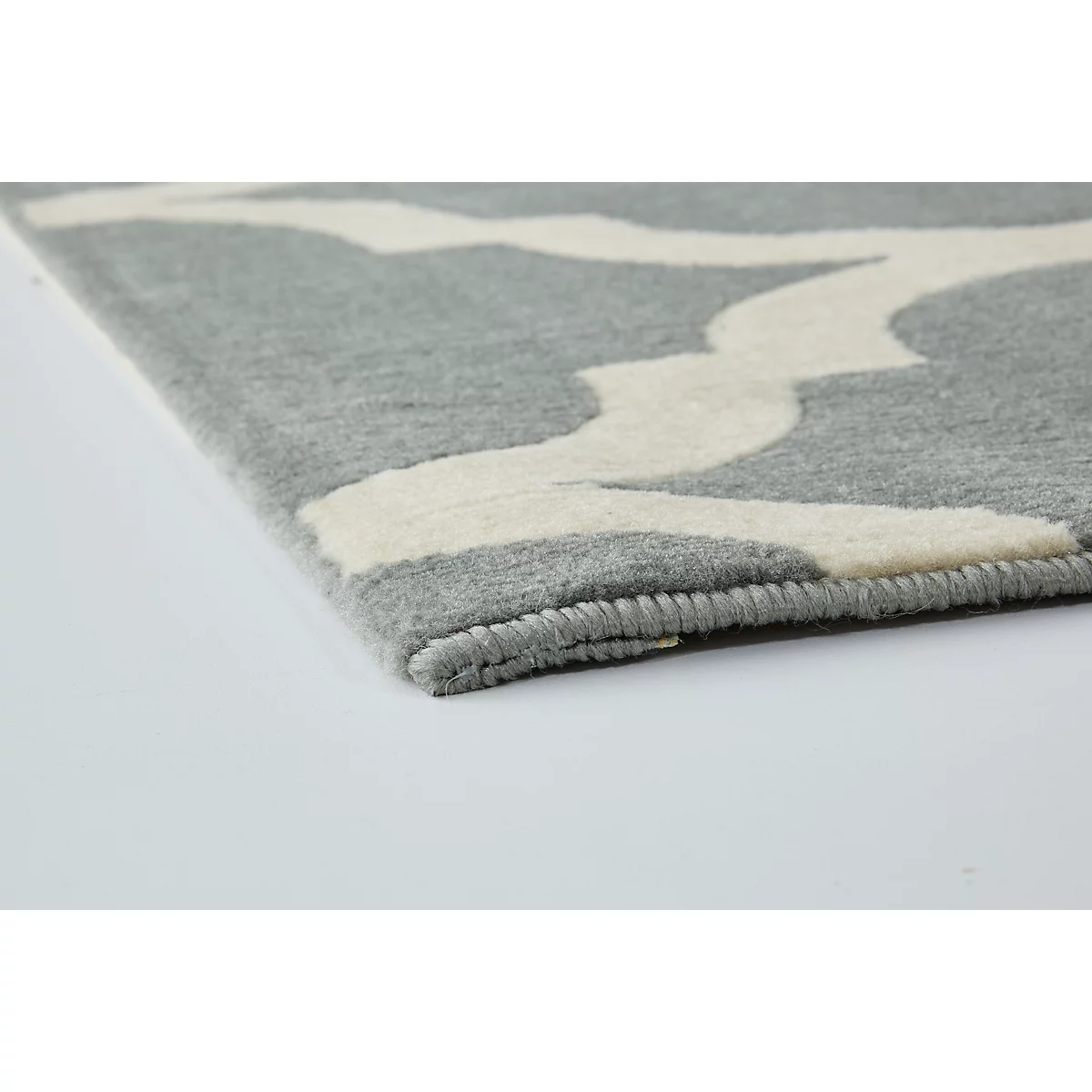 Close-up of a gray carpet with a white, curved pattern. The edge is rolled up.