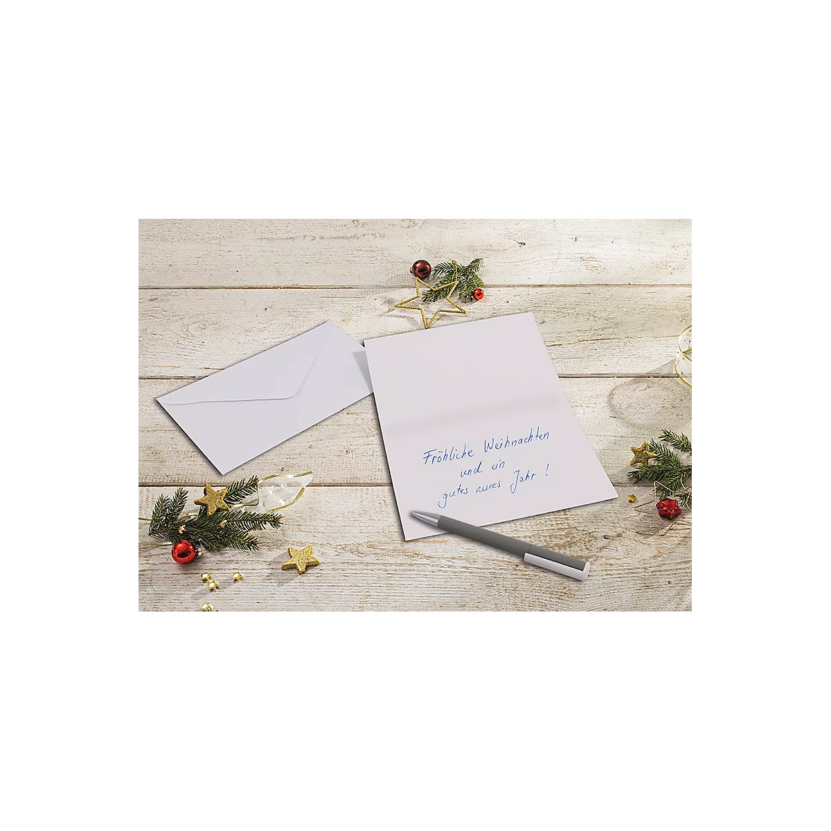 Carte de Noël avec message manuscrit, stylo, enveloppe et décorations de Noël sur fond de bois.