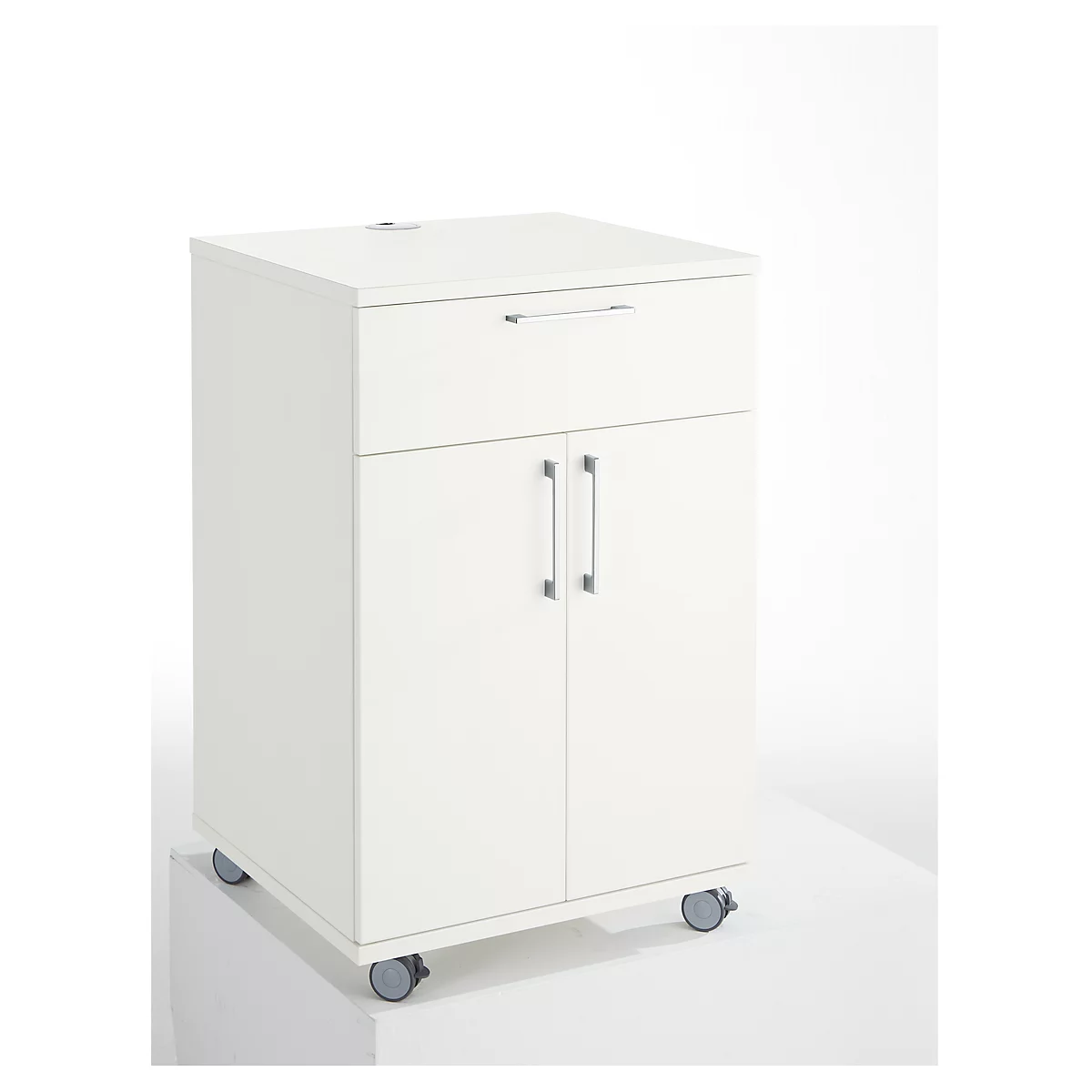 White cabinet on wheels, with drawer and double doors. Metal handles, neutral background.