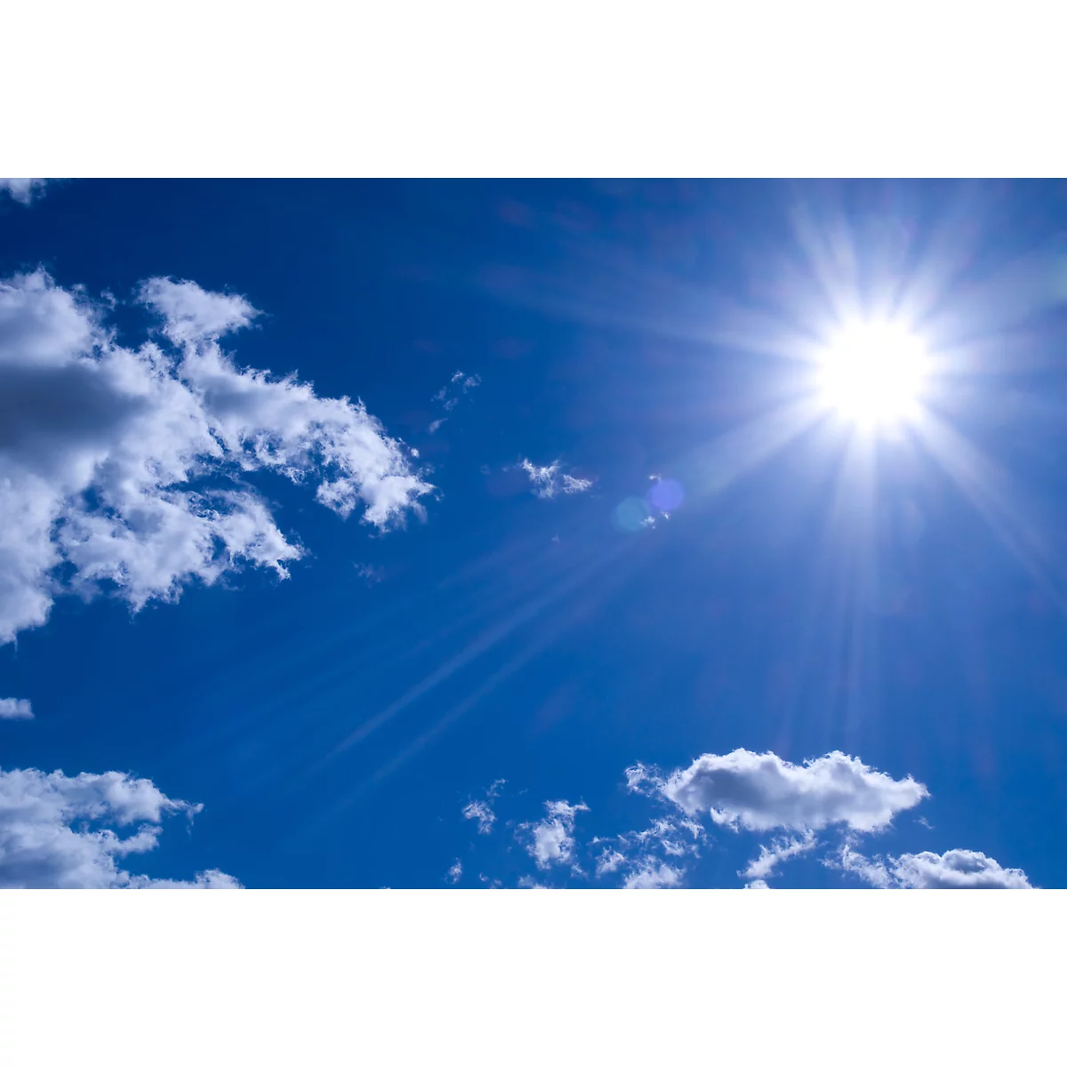 Blue sky with sun and clouds. The sun shines brightly, surrounded by rays of light.