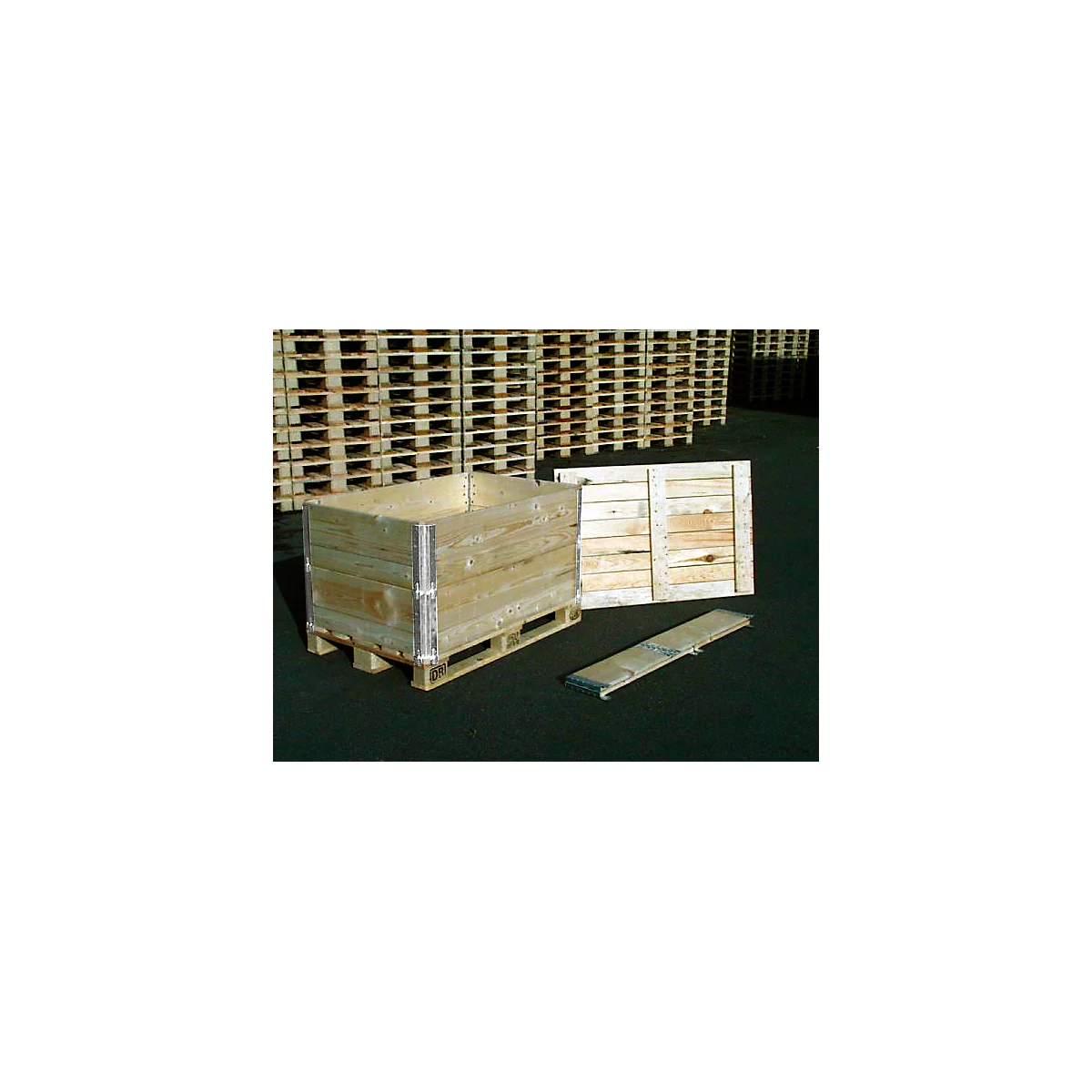 Caja de madera sobre palet con panel lateral extraído y pieza suelta.