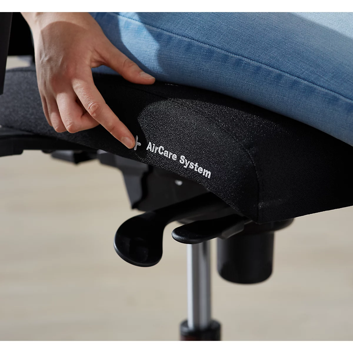 Une personne pointe le siège d'une chaise de bureau. La chaise porte l'inscription "AirCare System".