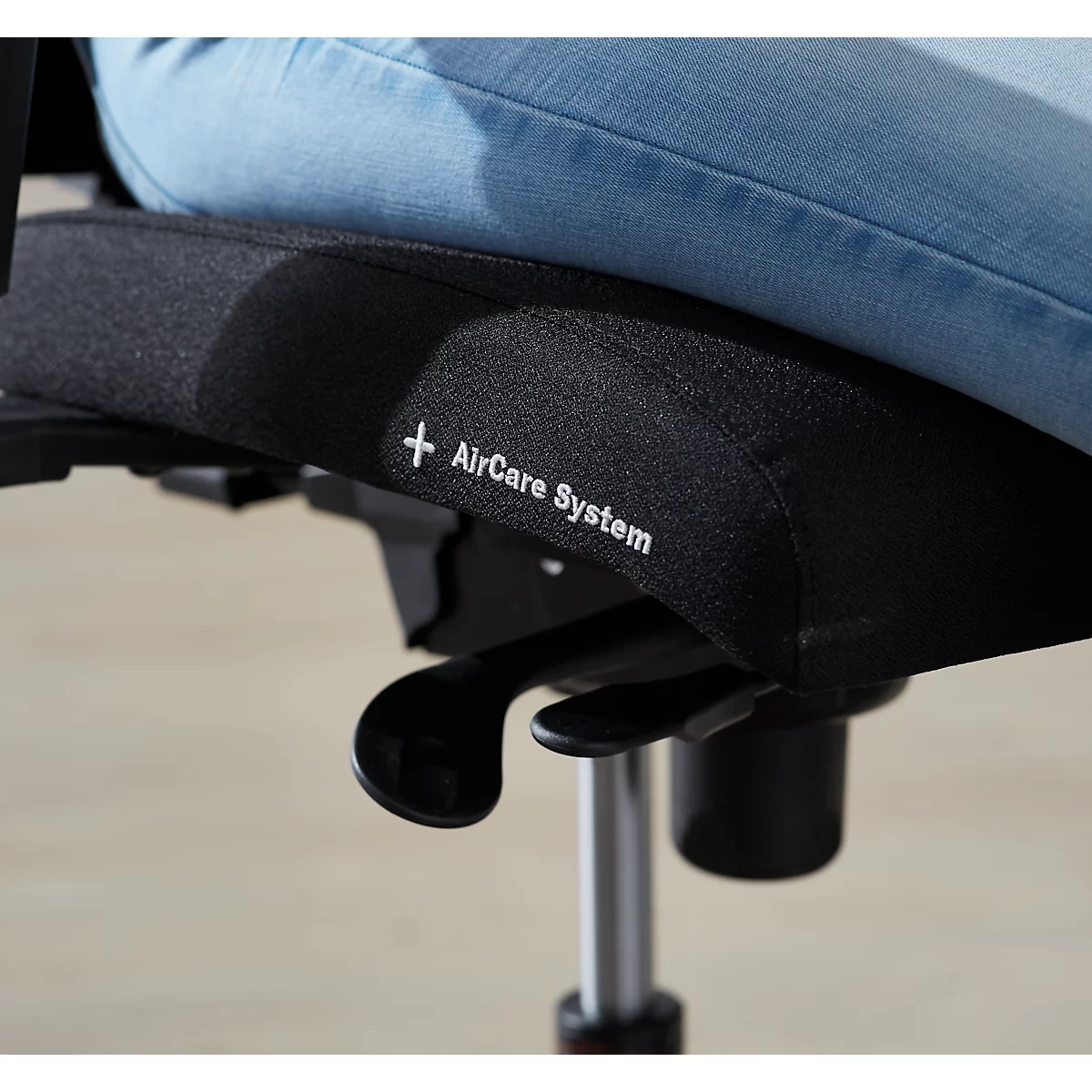 Gros plan d'une assise de chaise noire avec une personne en jean assise dessus. Le côté indique "+ AirCare System".