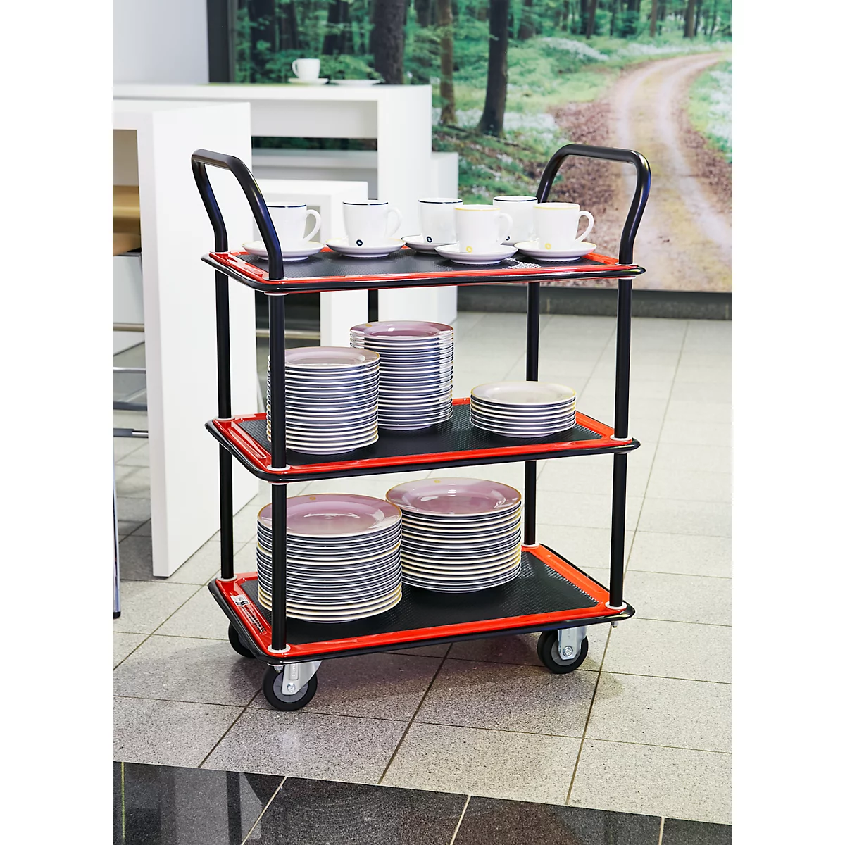 Un chariot de service avec tasses et assiettes. Cadre noir avec bordures et roues rouges. Fond avec motif forestier.