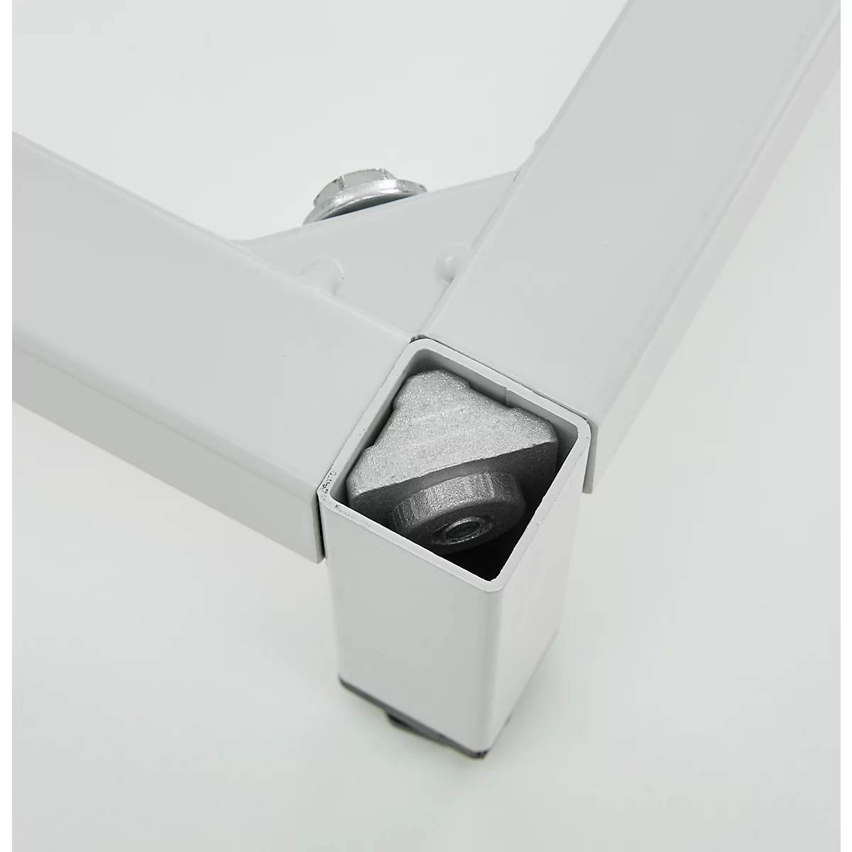 Gros plan d'une construction de pied de table blanche avec vis et raccords d'angle.