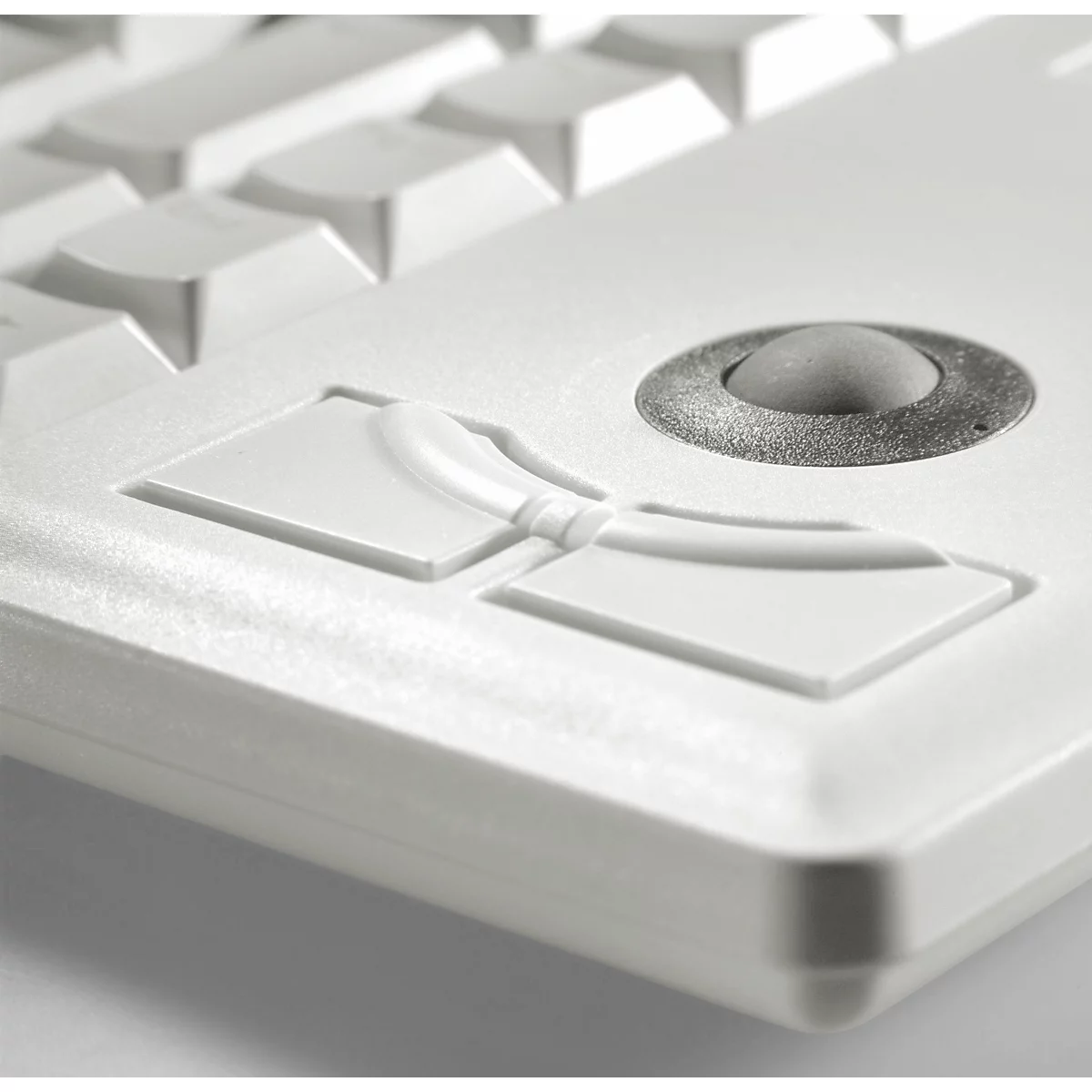 Close-up of a white keyboard with a trackball and buttons. The surface is bright and smooth.