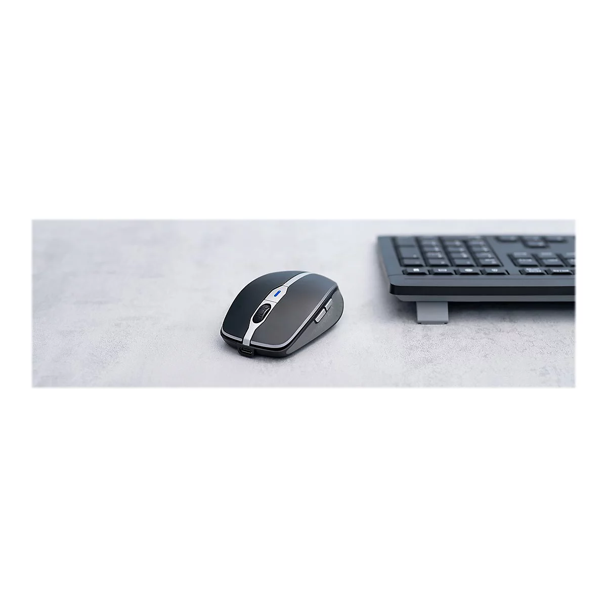 Drahtlose Computermaus mit silbernen Akzenten neben einer Tastatur auf einer hellen OberflÃ¤che.
